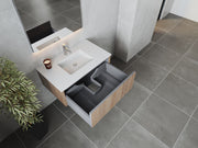 Bathroom vanity with open drawer, gray tiled floor, potted plant.