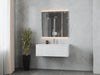Modern bathroom with floating vanity, illuminated mirror, potted plant, and gray tile.
