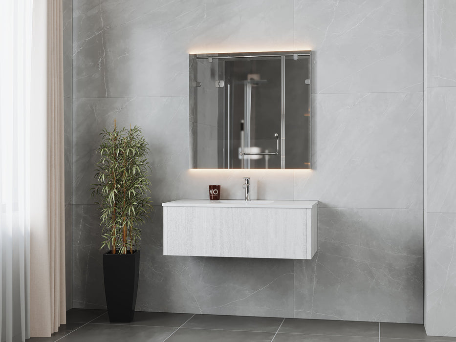 Modern bathroom with floating vanity, illuminated mirror, potted plant, and gray tile.

