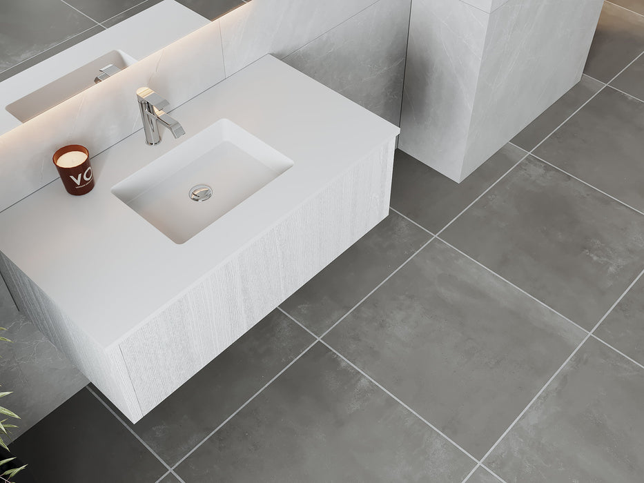 White sink with candle on gray tile floor.