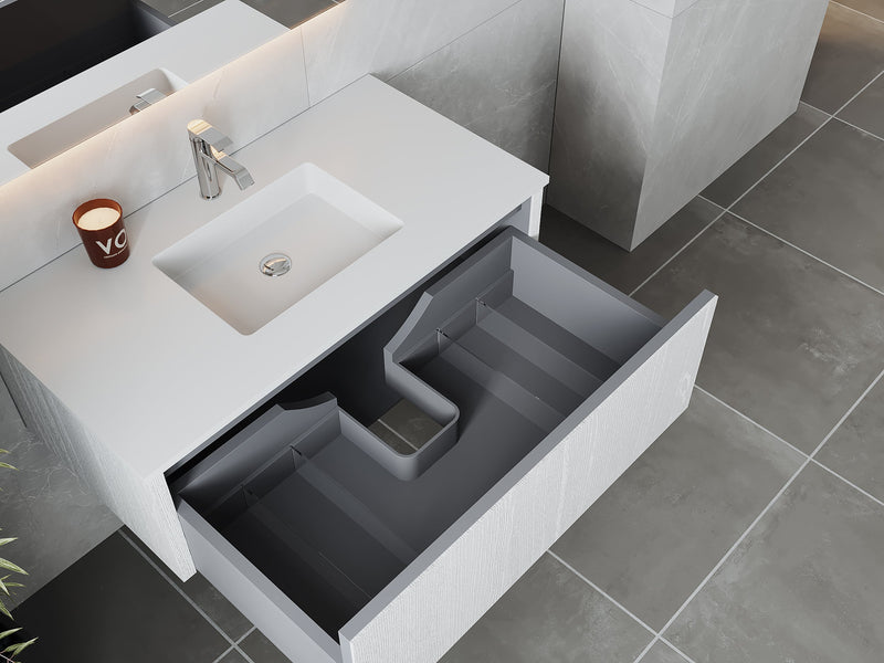 White vanity with open gray drawer, countertop sink, and silver faucet.
