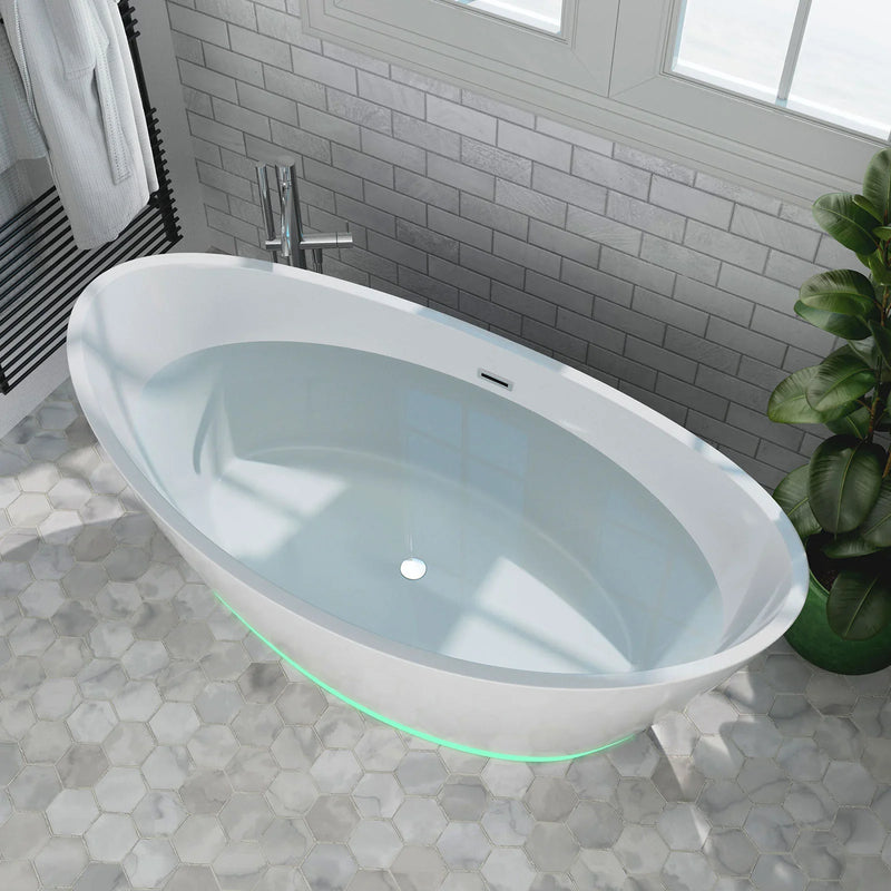 Modern white freestanding bathtub with green accent lighting, situated on hexagonal stone tiles and surrounded by gray subway tile walls and a houseplant.
