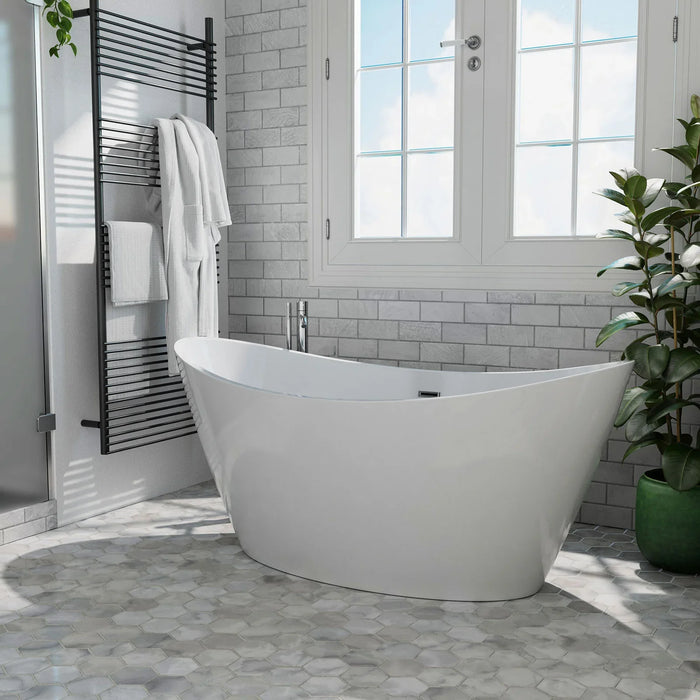 Modern white freestanding bathtub with sleek design, placed on hexagonal gray tiles beside a bright window with white towel rack and green potted plant.