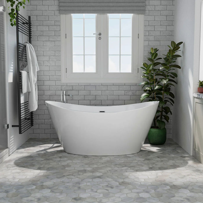 Modern white freestanding bathtub against gray brick wall, with French windows, towel rack, and potted plants creating a serene bathroom setting.