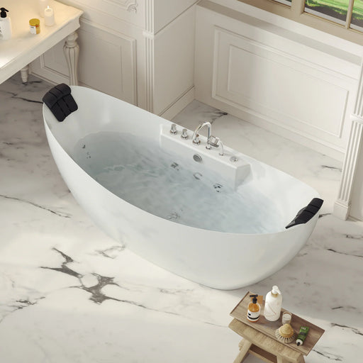Modern white freestanding bathtub filled with water, set on marble floor with bath accessories and a wooden side table in a bright, elegant bathroom.