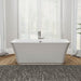 Modern white freestanding bathtub with chrome faucet, placed on a textured gray rug with hardwood floors and large windows in background.