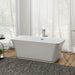 Modern white freestanding bathtub with chrome fixtures, positioned on a textured gray rug in a bright room with sheer curtains and wood flooring.