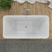 Modern white freestanding bathtub with chrome faucet, set against wooden wall with green plant and white towel.