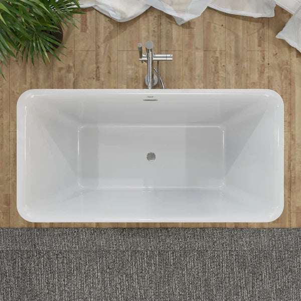 Modern white freestanding bathtub with chrome faucet, set against wooden wall with green plant and white towel.