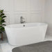 Modern white freestanding bathtub with sleek chrome faucet, placed on marble tile floor next to a potted green plant.