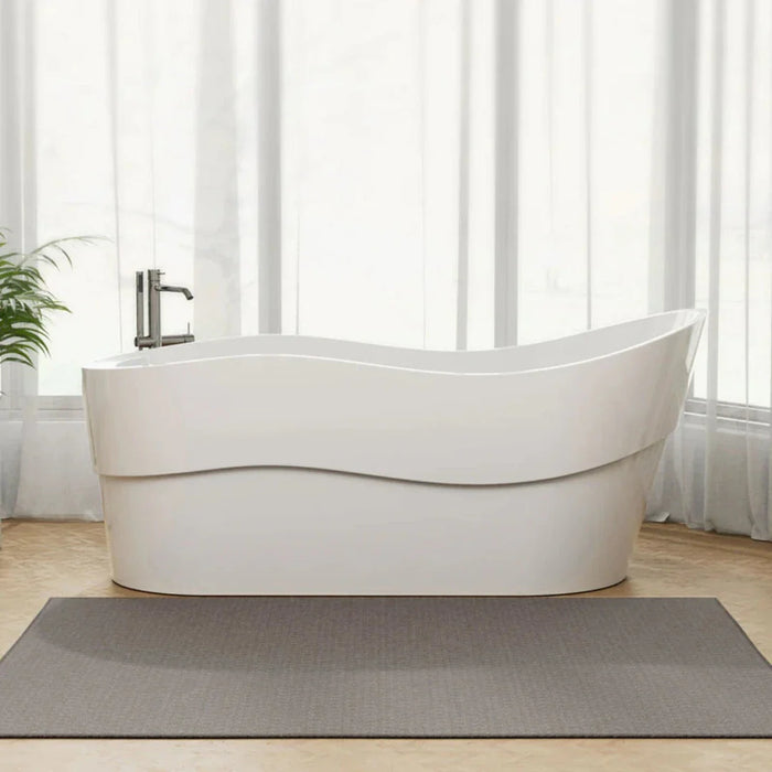 Modern white freestanding bathtub with curved lines, placed on a gray bath mat in a bright, minimalist bathroom with curtained windows and a green plant.