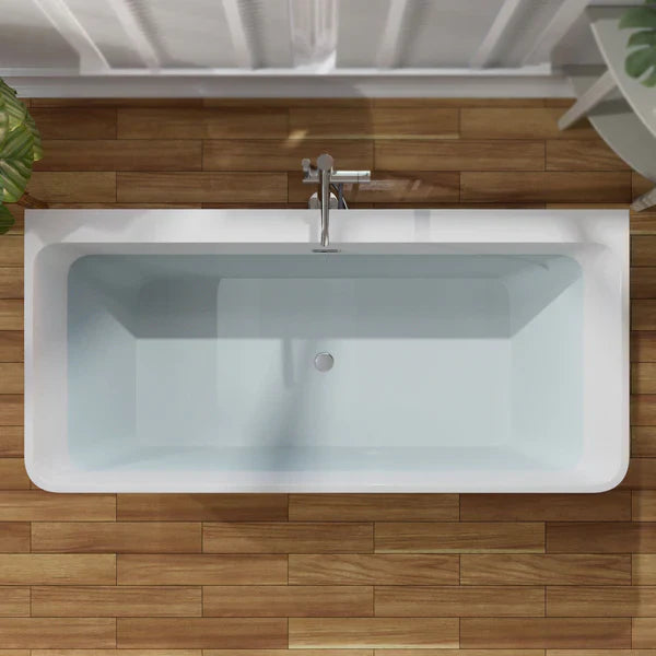 Modern white rectangular bathtub with chrome faucet, viewed from above on wooden floor with hints of green plant leaves.