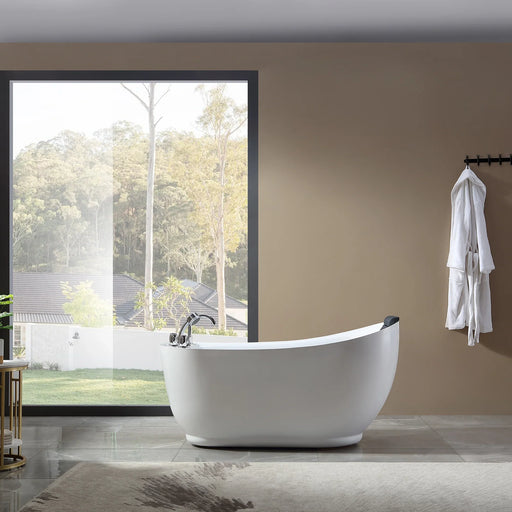 Modern white freestanding bathtub near large window, overlooking lush green trees and garden with white bathrobe hanging on wall