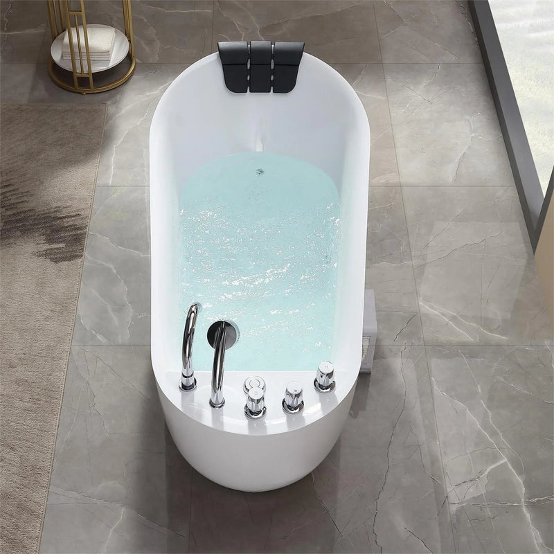 Oval white bathtub filled with teal water, chrome faucet fixtures, black headrest, on marble tile floor with gold towel stand.