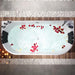 Luxurious bathtub filled with milky water, adorned with scattered red and white rose petals, surrounded by soft lighting and stone tiles.