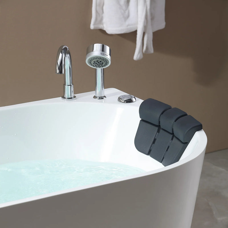 Modern white bathtub with chrome fixtures and a dark gray ergonomic bath pillow, water partially filling the tub.