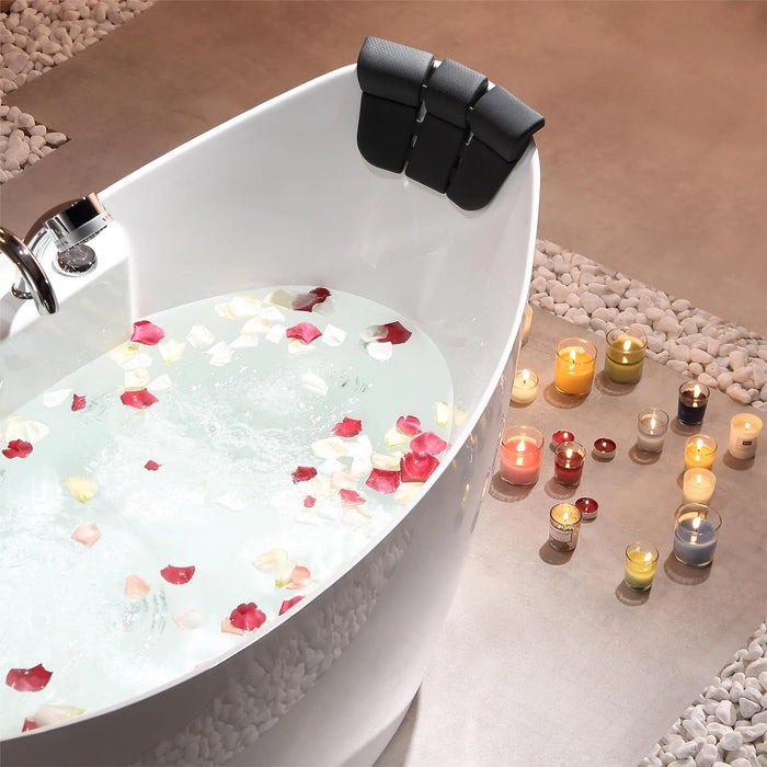 Tranquil bathtub scene with rose petals floating in water, surrounded by glowing candles on pebble-lined floor.