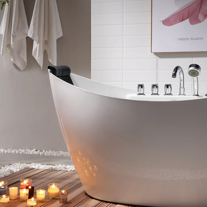 Modern white bathtub with lit candles on wooden floor, creating a relaxing spa-like bathroom atmosphere with white towels and a botanical art print.