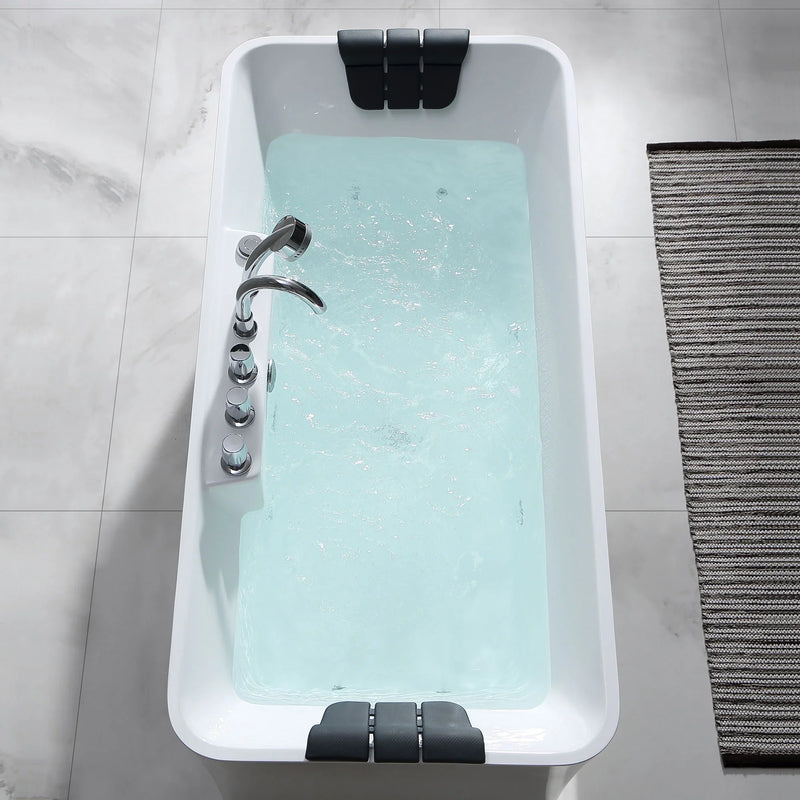 Modern white bathtub filled with light blue water, chrome faucet, black cushioned headrests at each end, on tiled floor with striped bath mat.
