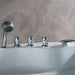 Chrome bathtub faucets and handheld showerhead on a marble-tiled wall with a white tub surface.
