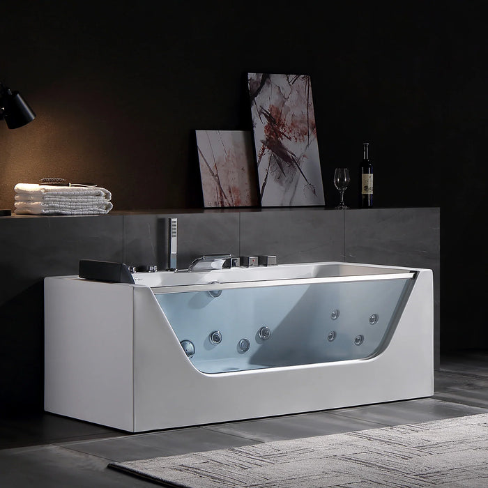 Modern white whirlpool bathtub with glass side panel, chrome fixtures, and abstract art on gray wall background