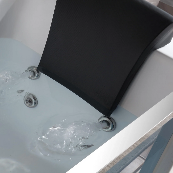 Close-up of a black headrest mounted on a white bathtub with running water from two jets.