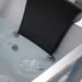 Close-up of a black headrest mounted on a white bathtub with running water from two jets.