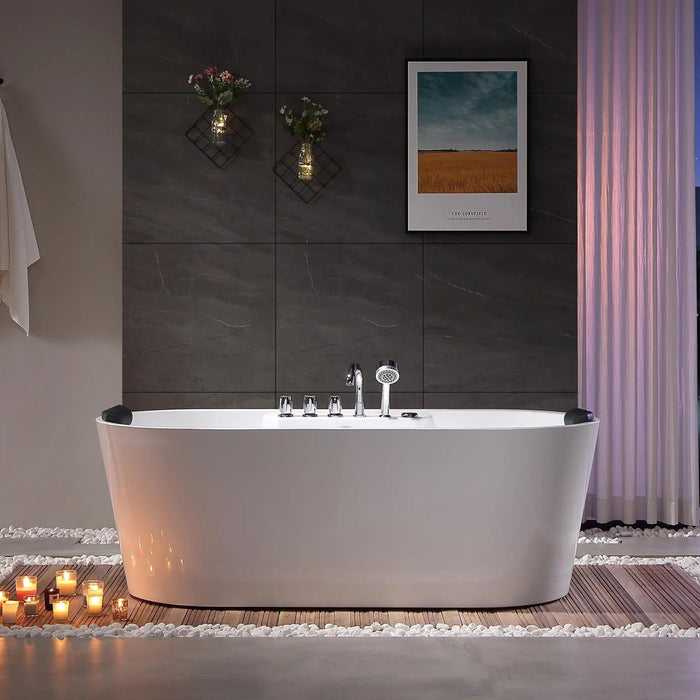 Modern bathroom with freestanding white bathtub, dark stone tiles, candles, floral decor, and landscape art, creating a serene spa-like atmosphere.