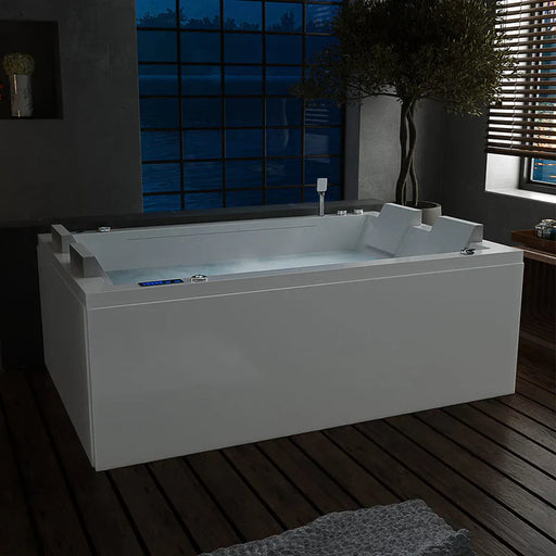 Modern white bathtub with digital controls, illuminated softly, positioned near large windows with night sky view and wooden deck flooring.