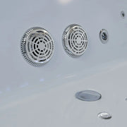 Metallic circular vents and drainage covers on a smooth, light gray surface of a hot tub or spa.