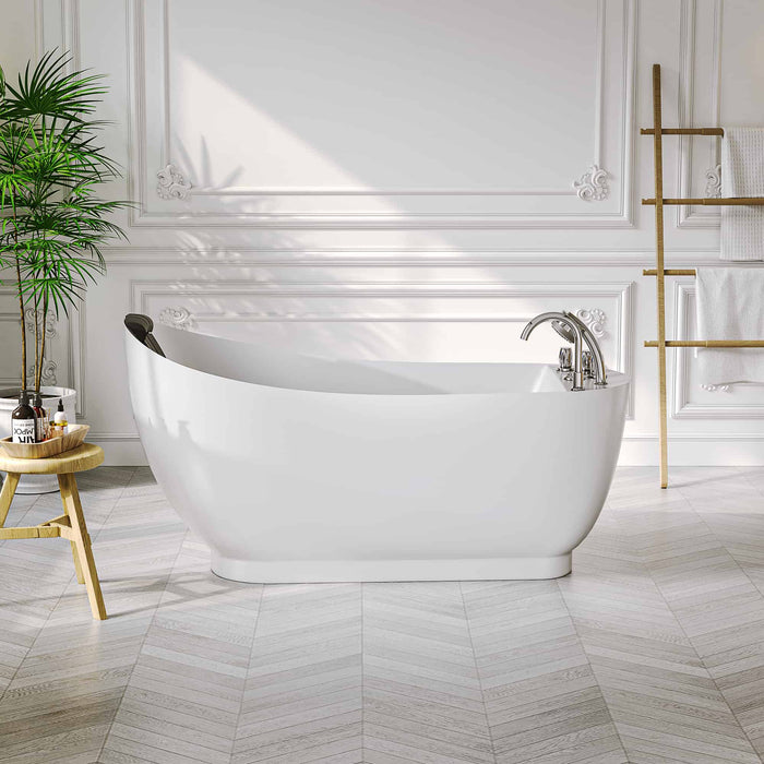 Modern white freestanding bathtub in elegant bathroom with herringbone floor, wooden side table, and potted palm plant.