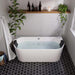 Modern bathroom with freestanding white tub, black hexagon floor tiles, subway wall tiles, and green plants creating a serene spa-like atmosphere.