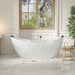 Modern white freestanding bathtub near large window overlooking green garden, with wooden side table and bath accessories.