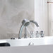 Modern chrome bath faucet with multiple controls and a running showerhead against a marble-like gray wall.