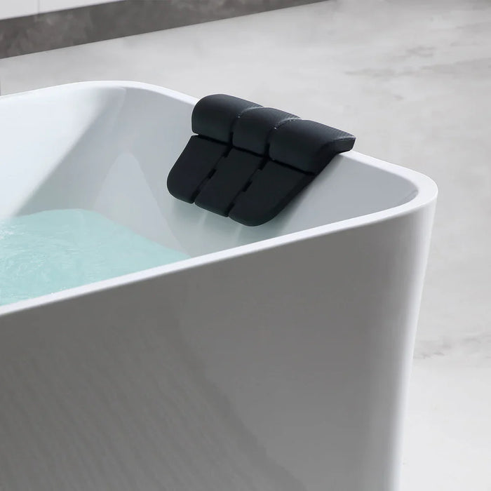 Black modular bath pillow resting on the edge of a white, curved bathtub with teal water.
