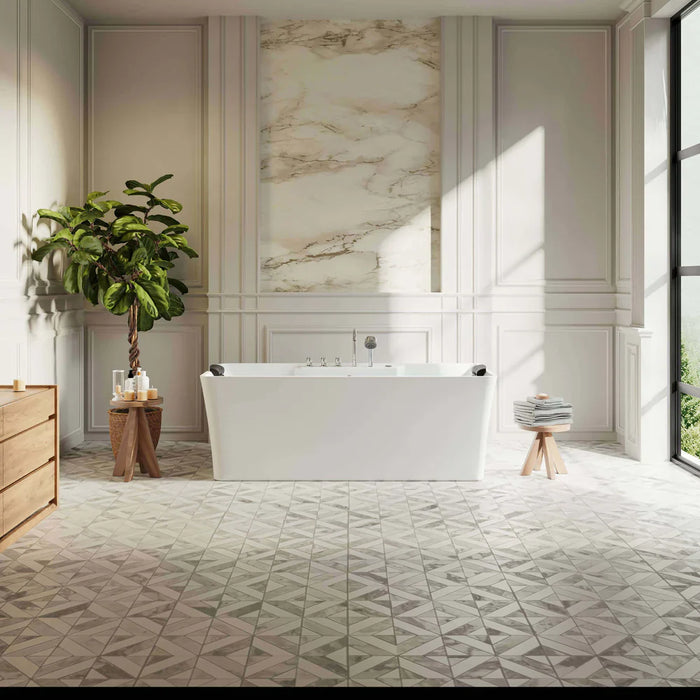 Elegant bathroom with white freestanding tub, marble accent wall, geometric floor tiles, and a potted fiddle leaf fig plant by a wooden side table.