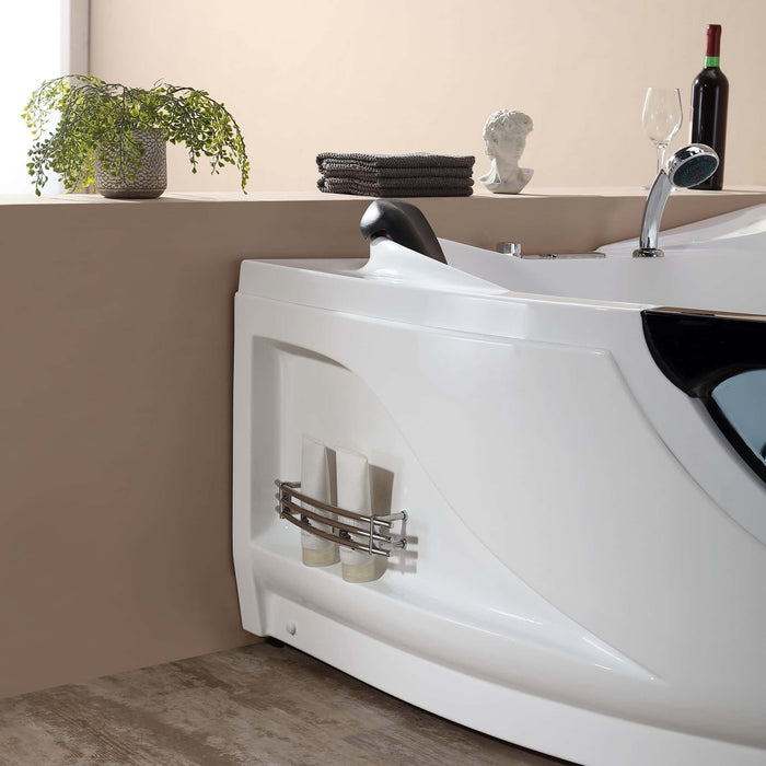 Modern white bathtub with curved design, small plant, towels, wine bottle, and decorative bust on shelf above.