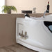 Modern white bathtub with curved design, small plant, towels, wine bottle, and decorative bust on shelf above.