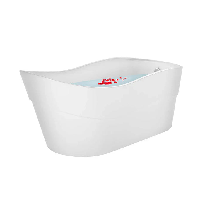 Modern white freestanding bathtub with blue water and small red rose petals floating on the surface.