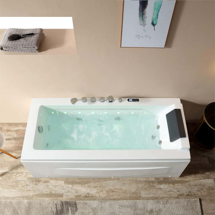 Modern white bathtub filled with blue-green water, featuring multiple jets and a digital control panel, positioned on a textured tile floor.