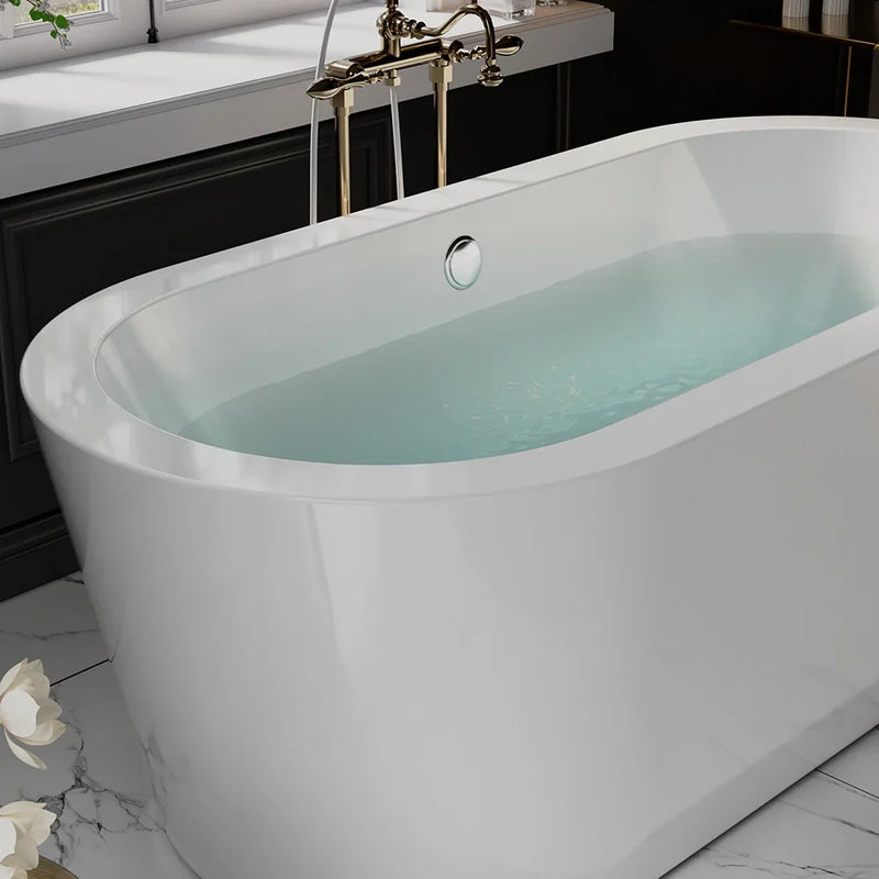 Modern white freestanding bathtub filled with pale blue water, vintage brass faucet, marble floor with white flower in foreground.