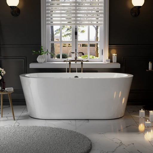 Modern white freestanding bathtub beneath a window with blinds, surrounded by dark walls, marble floor, and soft candlelight.