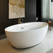Modern white freestanding bathtub with gold-tinted drip art on dark wall, elegant mosaic floor tiles visible.