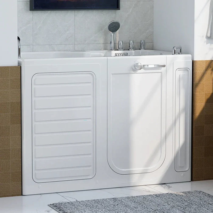 White walk-in bathtub with side door, shower head, and controls, installed against marble-tiled bathroom wall.