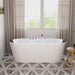 Modern white freestanding bathtub with chrome fixtures, positioned in front of sheer curtained windows with geometric tile floor and wooden stool.