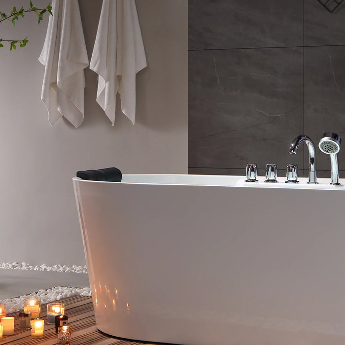 Modern white bathtub with chrome fixtures, surrounded by candles and white towels, creating a serene spa-like bathroom atmosphere.