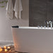 Modern white bathtub with chrome fixtures, surrounded by candles and white towels, creating a serene spa-like bathroom atmosphere.