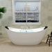 Modern white freestanding bathtub beneath a window with white blinds, set against hexagonal light-colored tiles.