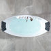Modern oval bathtub filled with blue-green water, viewed from above on a gray marble tile floor, with chrome fixtures and black side supports.
