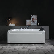 Modern white bathtub with chrome fixtures, positioned on textured floor against dark gray wall with art and lamp